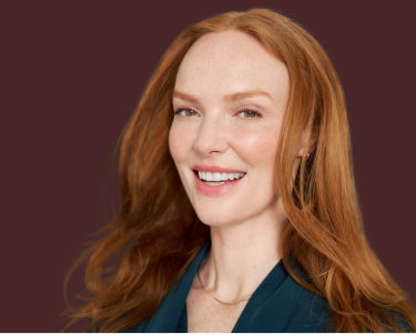 長い赤みがかった髪の人物がダークなジャケットを着ています