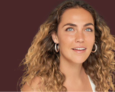 大きなフープイヤリングを着け、長くカールした髪が肩にかかっている様子の詳細な画像