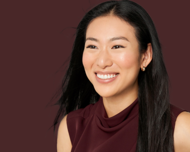 長い黒髪の人物がマルーントップを着ています